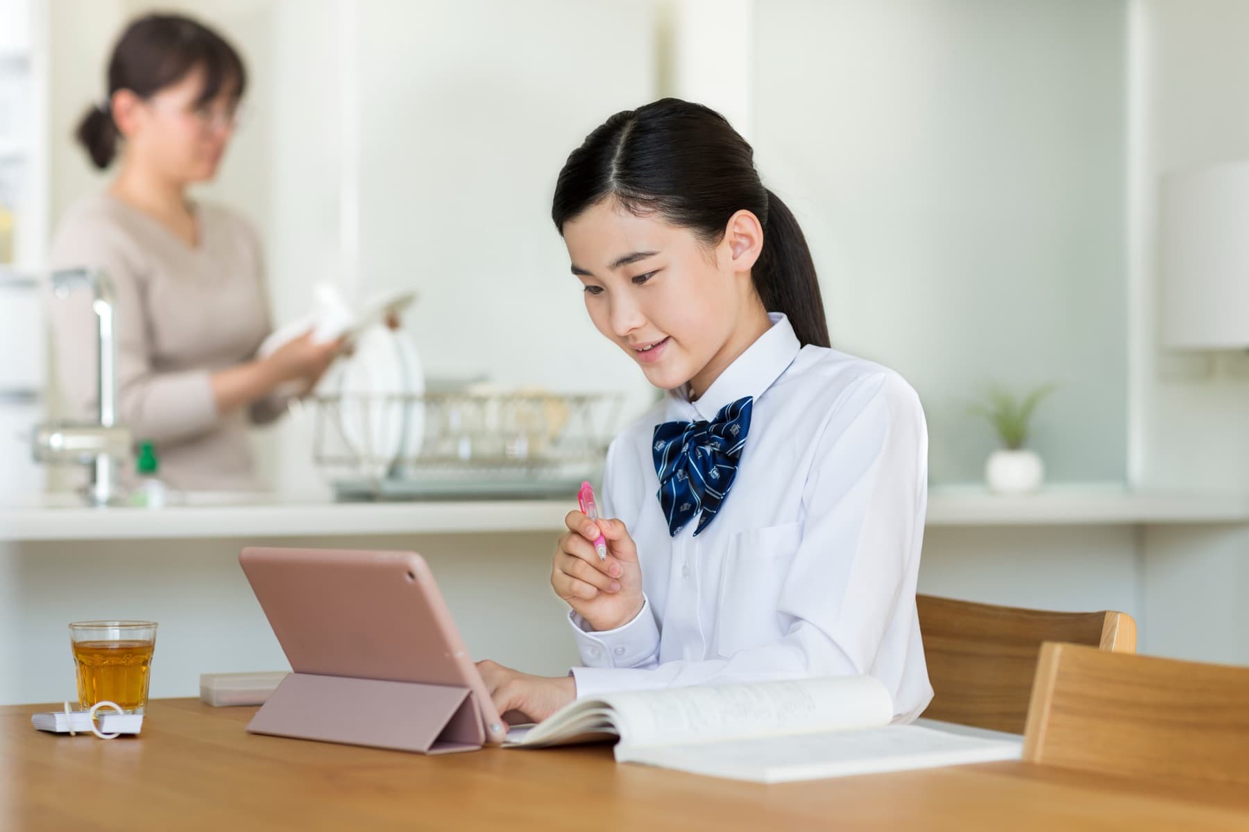 自宅でタブレットを使い学習する女子中高生